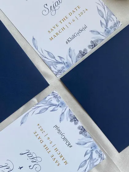 A closer look at the soft blue floral palette used for these "Save The Date" cards. The design combines printed text with spot calligraphy for the couple's names, creating a balanced and beautiful announcement.
