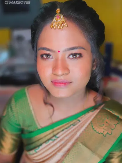 A close-up of this bride's engagement look, featuring a simple green and cream saree. The makeup is minimal and fresh, with a pop of pink on the lips.