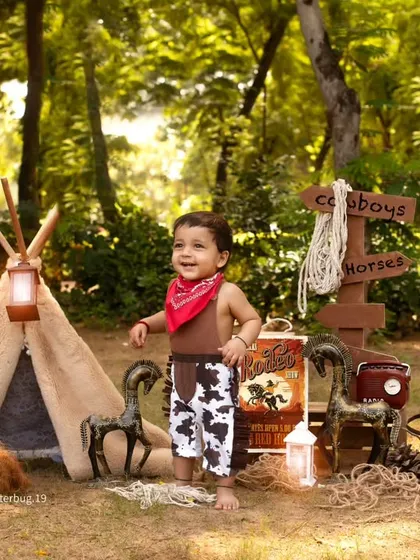 A happy little cowboy exploring the woods in our outdoor adventure setup, complete with a teepee and rustic props.