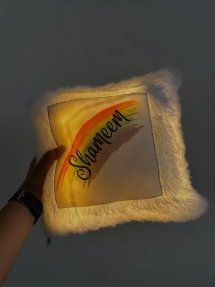 Holding up the glowing 'Shameem' LED cushion to show its brightness.