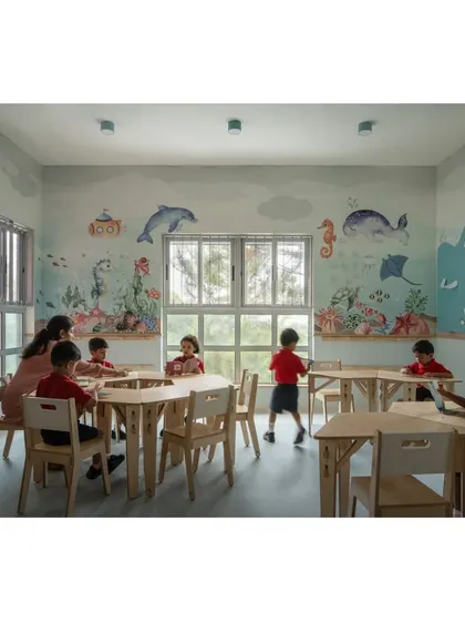 Dive into the aqua-themed classroom for UKG students. The walls are adorned with a vibrant underwater scene, complete with whales, dolphins, and coral reefs, creating a dynamic and engaging learning space.