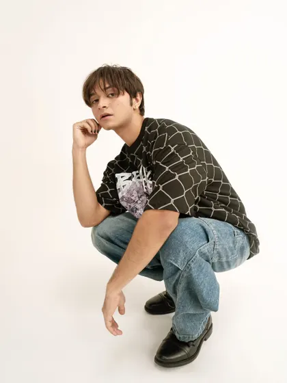A classic lookbook pose for a men's streetwear brand. The clean background and simple pose keep the focus on the graphic tee and baggy jeans.