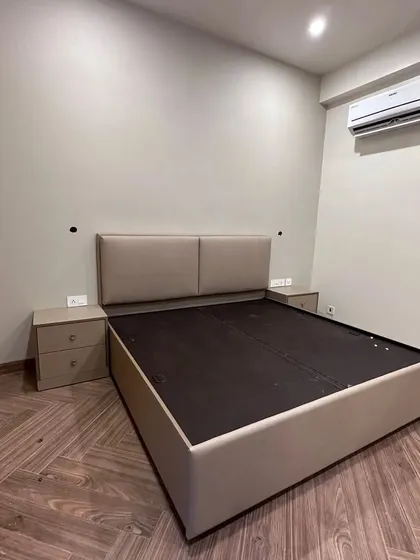 A bespoke upholstered bed with a matching headboard and side tables, customized to the client's needs. This image shows our furniture before final placement, highlighting the craftsmanship.