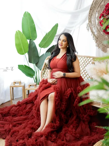 A beautiful portrait of a mom-to-be in a boho-chic setting. Her rust-colored gown and the natural textures of the studio create a warm and inviting atmosphere.