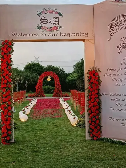 The "Once Upon a Time" storybook entrance leads guests towards the main ceremony area. The red rose-covered aisle and floral arch create a fairytale path for the couple's new beginning.