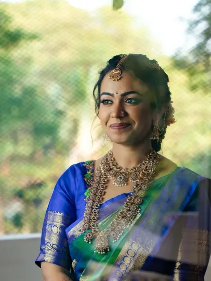 A lovely shot through a window, adding a soft, dreamy quality to the bride's look. Her radiant smile is the centerpiece.