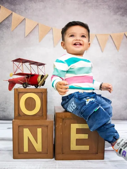 Ready for takeoff! This little boy celebrates turning one with a cheerful smile, sitting beside a vintage toy airplane prop.