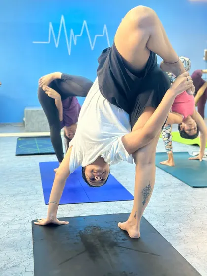 A student smiling through a challenging standing split variation. The joy is in the journey.