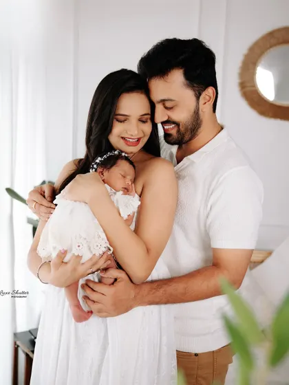 An intimate family portrait with a newborn. The parents are holding their sleeping baby, creating a feeling of warmth, love, and togetherness.