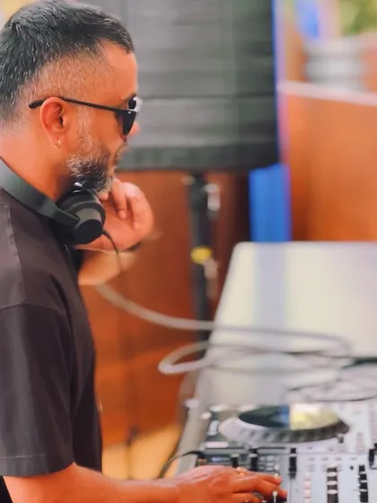 A side profile shot while I'm in the middle of a mix at a daytime party. It's all about finding that perfect groove to match the bright and airy feel of the event.