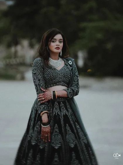 A full-length portrait of the bride in her dark, elegant lehenga, her confident pose exuding grace and style.