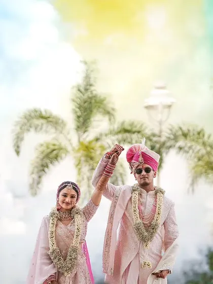 A grand, celebratory shot of the couple with colored smoke and palm trees, perfect for a destination wedding.