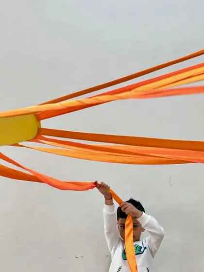 Three young students proudly hold up the rays of a sun prop. Our classes often involve group activities that foster a sense of community and shared accomplishment.