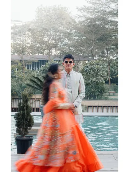A creative motion-blur shot of the bride in her vibrant orange lehenga, adding a dynamic and artistic feel to their poolside Haldi portraits.