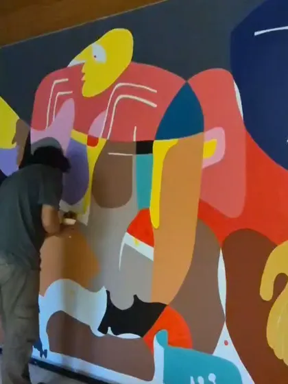 A team member painting a section of the vibrant, Picasso-esque mural.