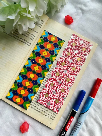 A pair of handmade geometric bookmarks. The one on the left is bright and colorful, while the one on the right is an elegant red, gold, and silver design. These are available for purchase.
