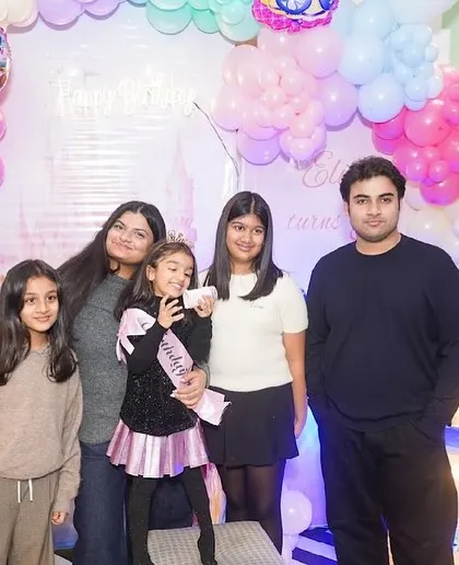A family poses together in front of a beautiful Frozen-themed balloon arch.