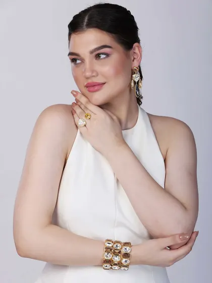 A profile view of the model, drawing attention to the intricate design of the earrings and the way they complement the bracelet and ring.