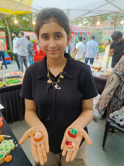 A young participant is delighted with the two dessert-themed candles she created at our outdoor event booth. Our activities are fun for all ages.
