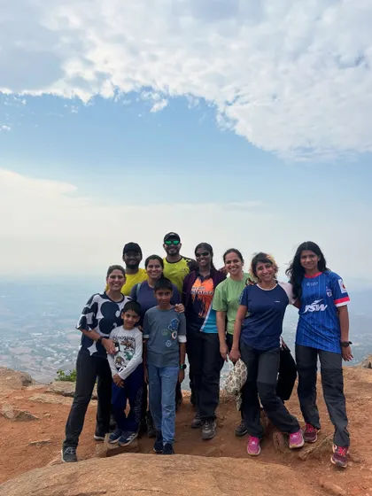 A diverse group of trekkers, including a family, smiling for a group photo at the summit. Our treks bring people from all walks of life together.