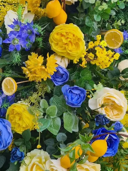 A close-up of the floral arrangement, showcasing the mix of yellow and blue roses and the creative use of sliced lemons as a decorative element.