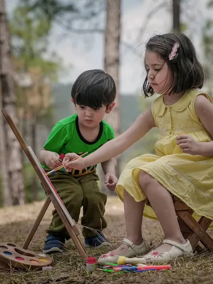 A brother and sister collaborate on a painting during a creative and fun outdoor art-themed shoot.