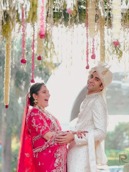 A moment of pure, uninhibited laughter between the couple under their wedding mandap. This candid shot perfectly captures the joy of their special day.