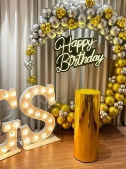 A personalized birthday setup with "GS" marquee letters and a gold and silver balloon ring.