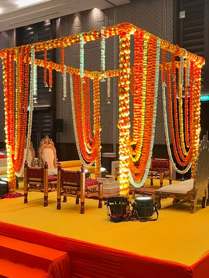 The beauty of a traditional wedding is timeless. This Vidhi Mandap is heavily decorated with strings of orange and yellow marigolds, creating a vibrant and auspicious setting for a Ganesh Puja or wedding ceremony.