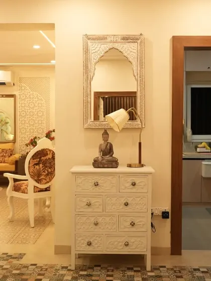 A view of a home's entryway, featuring a vintage-style chest of drawers and a traditional mirror.