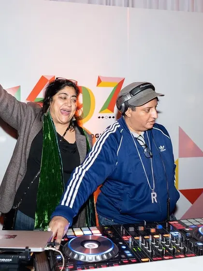 Sharing a laugh with a friend behind the decks at a gala. Even at formal events, the vibe is always about joy and connection.