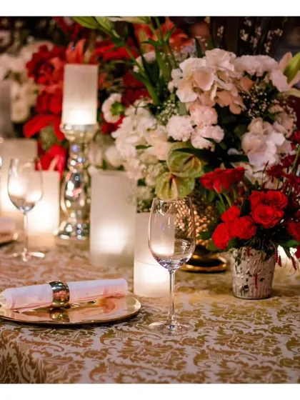 A close-up of a luxurious table setting with a red and white floral theme, showcasing our ability to create a romantic and opulent atmosphere.