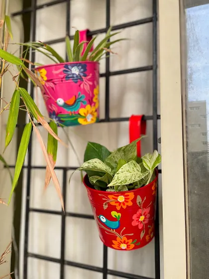 A pair of our hand-painted railing planters, adding a splash of color to a balcony window.