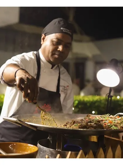 A chef preparing a large quantity of food on a tawa, demonstrating our capacity to handle large crowds without compromising on freshness.