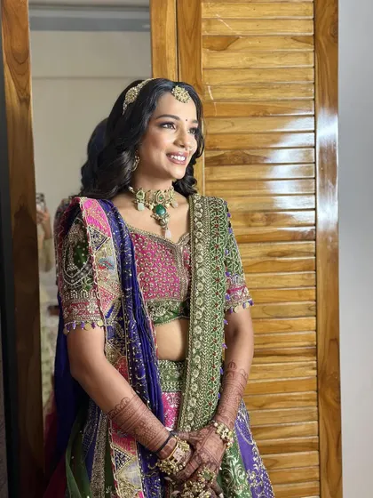 The sister of the groom, looking like a Radharani in this colourful lehenga. The makeup is bright and glowing, perfect for a wedding celebration.