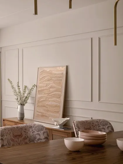 A detail of the dining area in "Apartment 222," focusing on the custom sideboard and the textured artwork leaning against the wall. The combination of wood, fabric, and art creates a space that is both functional and beautiful.