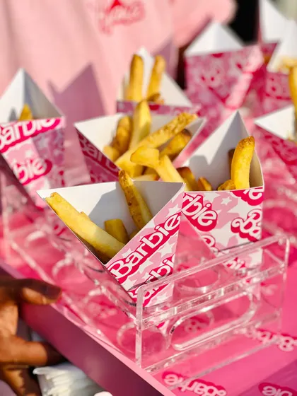 Crispy french fries served in triangular Barbie-branded cartons, presented in a clear acrylic holder for a clean, modern look.