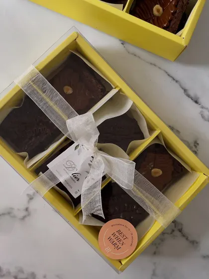 Our box of six fudgy, eggless brownies, featuring both classic chocolate and hazelnut flavors. Made with premium couverture chocolate, they are best enjoyed warm. The clear-lid box and elegant ribbon make it a perfect ready-to-gift treat.