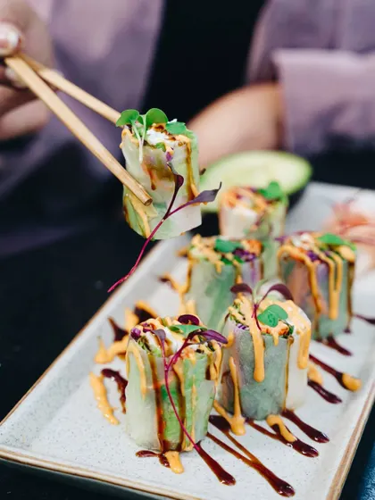 The simple action of picking up a piece of sushi with chopsticks makes the visual interactive. It draws the viewer in and highlights the fresh, beautifully presented dish.