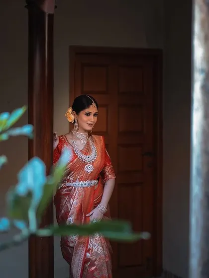 A candid portrait of the bride in a quiet corner. The soft, natural light and the framing by the plant in the foreground create a gentle, intimate feel.