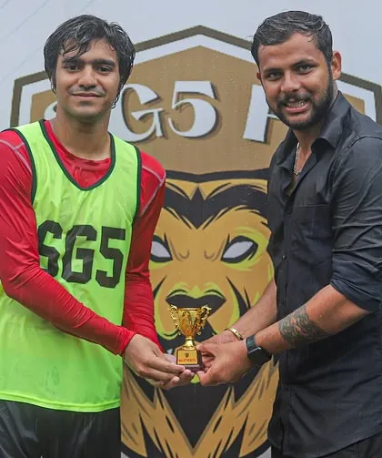 A player in a training bib receiving his Player of the Match award, showing that hard work in every session pays off.
