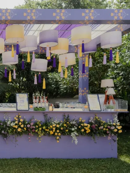A full shot of the pastel Haldi cocktail bar, nestled in a lush green lawn. The design is both functional and beautiful, serving as a central hub for guests to mingle.