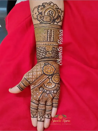 A detailed siders henna design covering one full arm. This piece combines floral bands, peacock motifs, and geometric patterns, making it a substantial and beautiful choice for a close relative.