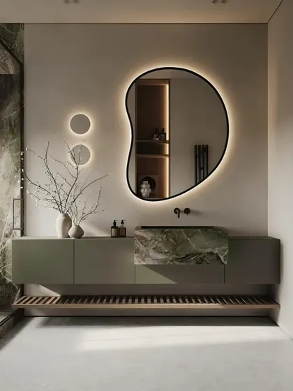 A serene and artistic bathroom with a unique, organically shaped mirror. The green marble integrated sink is a stunning feature, and the minimalist vanity keeps the look clean and modern.