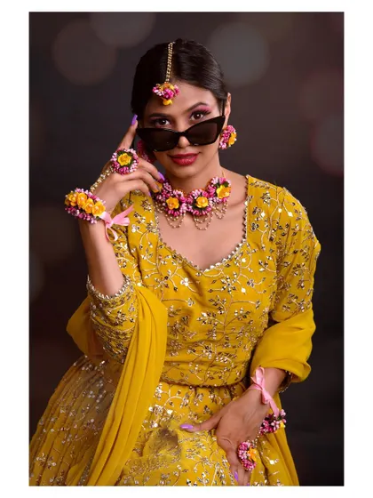 A fun and quirky shot of a model in a yellow lehenga and sunglasses. This image shows a modern, playful take on traditional wear.