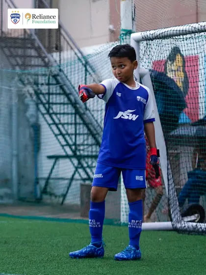A young goalkeeper stands ready and focused in front of the goal. We provide specialized training for all positions, ensuring every player develops the specific skills they need.