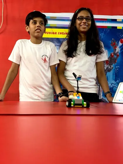 Teamwork makes the dream work. Two of our older students prepare their co-programmed robot for a competition, demonstrating advanced building and coding skills.