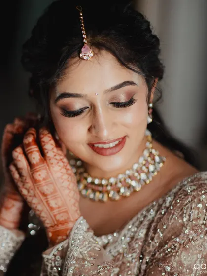 A detailed shot of the bride's makeup as she puts on her earring. You can see the flawless eyeshadow blending and the beautiful highlight on her skin.