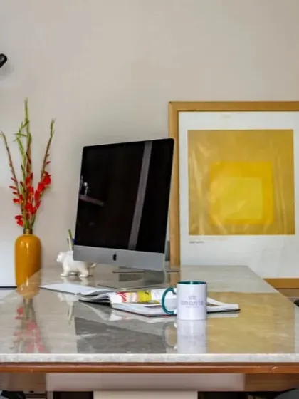 A detail shot of an executive desk, showing how we curate art and decor to personalize a workspace. The clean lines of the desk and shelving are softened by colorful art and personal items.