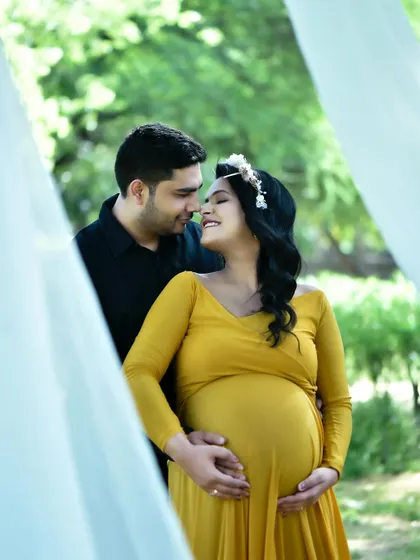 An intimate couple's portrait taken during an outdoor maternity shoot. This candid moment captures the connection between the parents-to-be, framed by natural light and greenery.